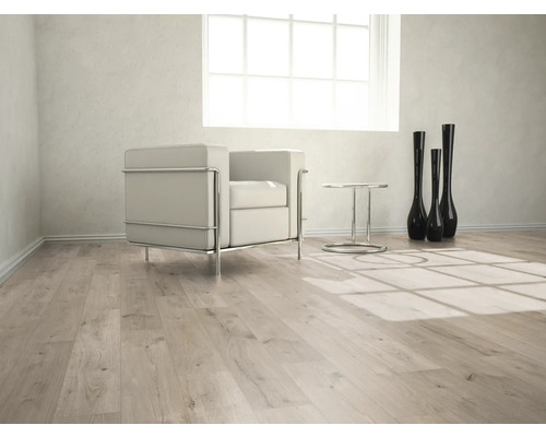 Heller Raum mit Laminatboden, Sessel, Tisch und Dekovasen.