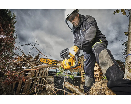 Ein Mann mit Schutzausrüstung verwendet eine DeWalt Kettensäge zum Beschneiden von Ästen.