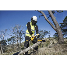 Eine Person mit Schutzausrüstung schneidet mit einer DeWalt Kettensäge einen Baumstamm.