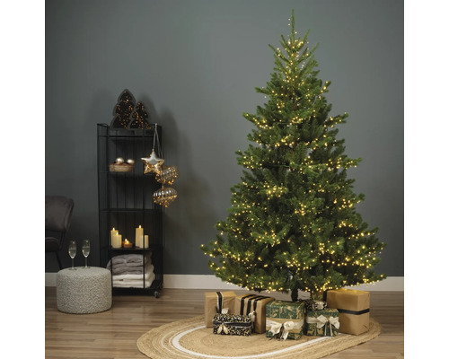 Weihnachtsbaum mit Lichtern und Geschenken auf einem Teppich in einem Wohnzimmer