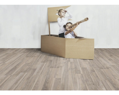 Zwei Kinder spielen in einem Pappboot auf einem Holzboden.