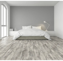 Schlafzimmer mit Bett, Nachttischlampe und Holzboden.