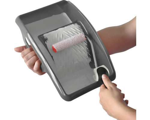 Eine Person hält eine Farbwanne mit Farbroller in der Hand