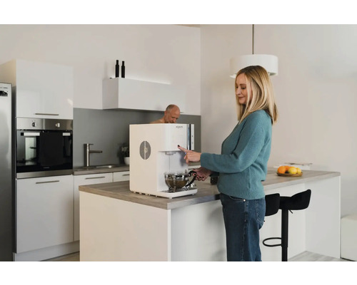 Frau bedient Wasserspender in einer hellen Küche