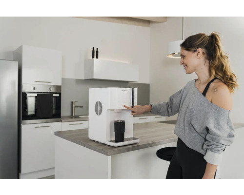 Frau bedient Wasserspender in moderner Küche