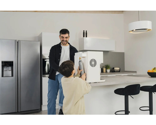 Vater und Sohn tauschen eine CO2-Flasche in einem Wassersprudler in einer modernen Küche aus