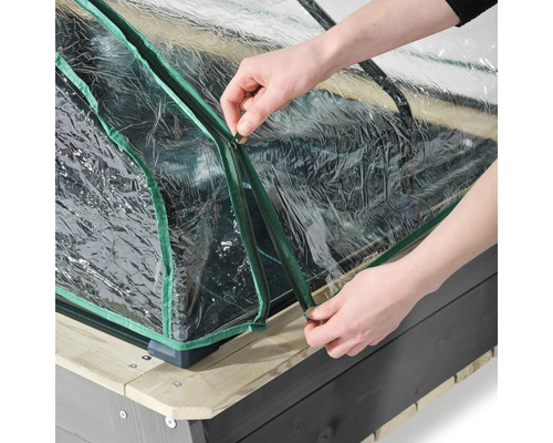 Detailansicht eines Frühbeetaufsatzes mit Reißverschluss über einem Hochbeet, der von Händen bedient wird.