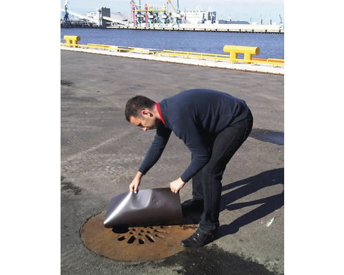 Eine Person versucht, einen Gullydeckel mit einer Metallplatte zu verschließen.