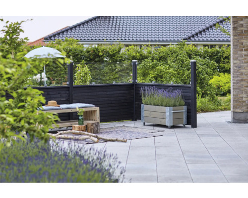 Außenbereich mit Zaunelementen aus Holz und Glas, Sitzbank mit Polsterauflage, Blumentopf mit Lavendel und Steinboden