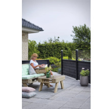 Terrassenszene mit Palisadenzaun, Palettenmöbeln und einer Frau, die ein Buch liest