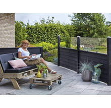 Terrassenszene mit Frau auf Palettensofa, Palettentisch und Sichtschutzzaun