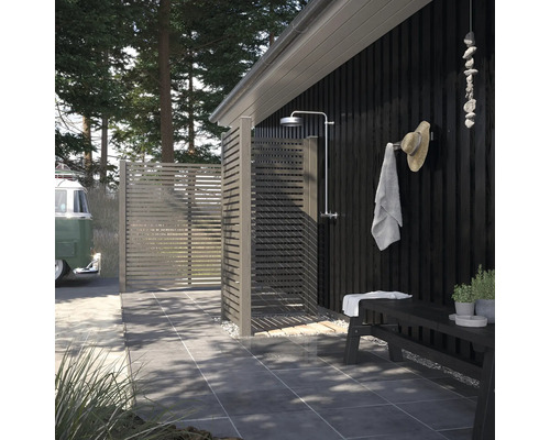 Außendusche mit Holzwänden, Duschkopf und Sitzbank im Garten.