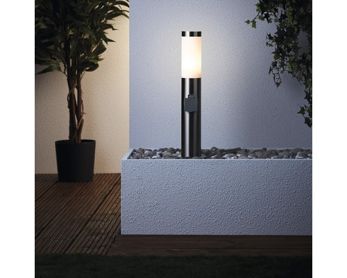 Beleuchtete Sockelleuchte in einem mit Steinen gefüllten Blumenkasten neben einer Pflanze