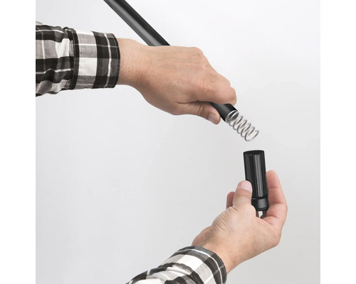 Eine Person montiert eine Metallfeder an einem schwarzen Stab.