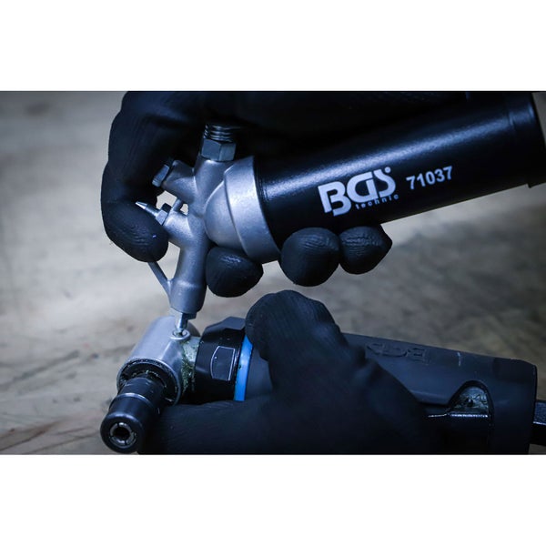 Person mit Handschuhen verwendet eine BGS Technic Fettpresse 71037 zur Wartung eines Werkzeugs.