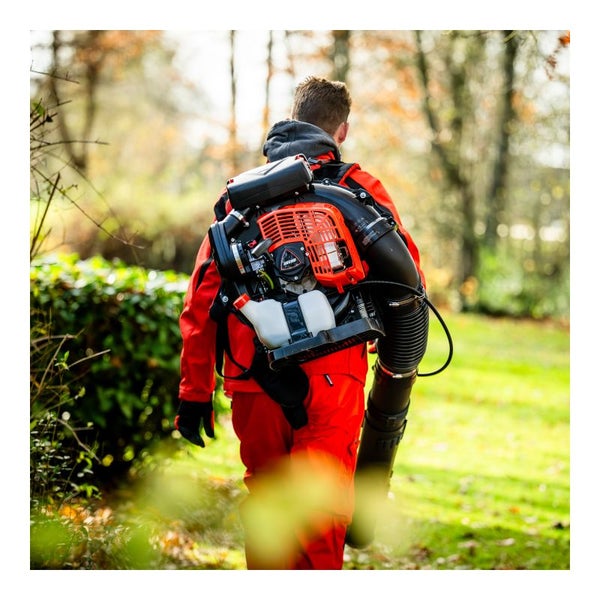 Person mit tragbarem Laubbläser im Garten