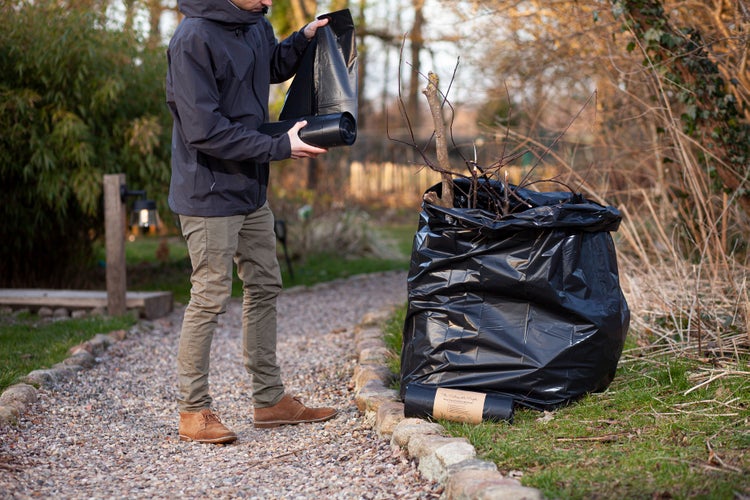 Gartenabfallsack mit Person und Gartenabfällen im Freien