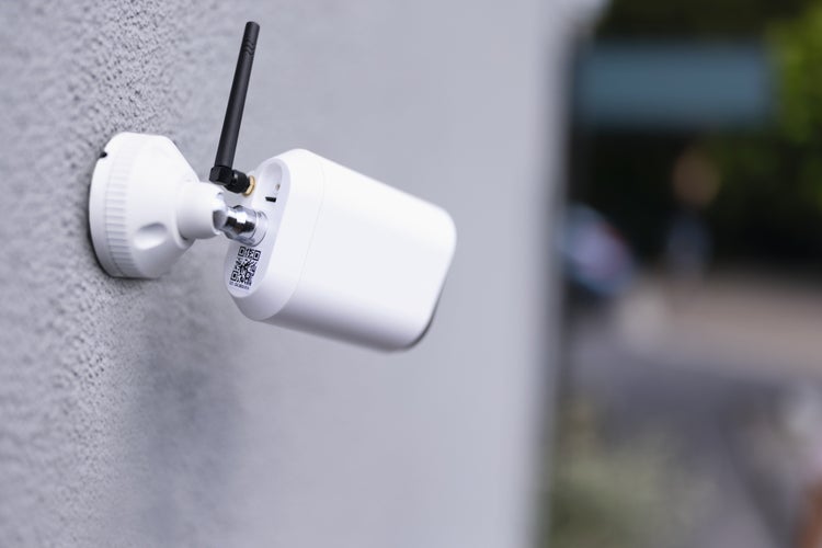 Weiße Überwachungskamera für den Außenbereich mit Antenne und Wandhalterung.