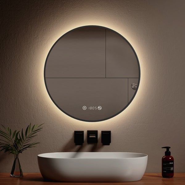 Runder Badezimmerspiegel mit LED-Beleuchtung und Digitalanzeige über einem weißen Aufsatzwaschbecken mit schwarzen Armaturen.