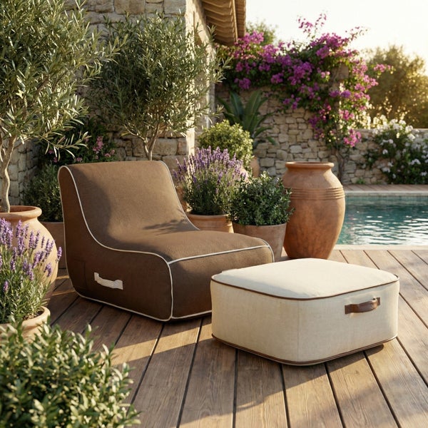 Brauner Outdoor-Sitzsack und beiger Hocker auf einer Holzterrasse am Pool mit Olivenbäumen und Lavendel in Terrakotta-Töpfen.