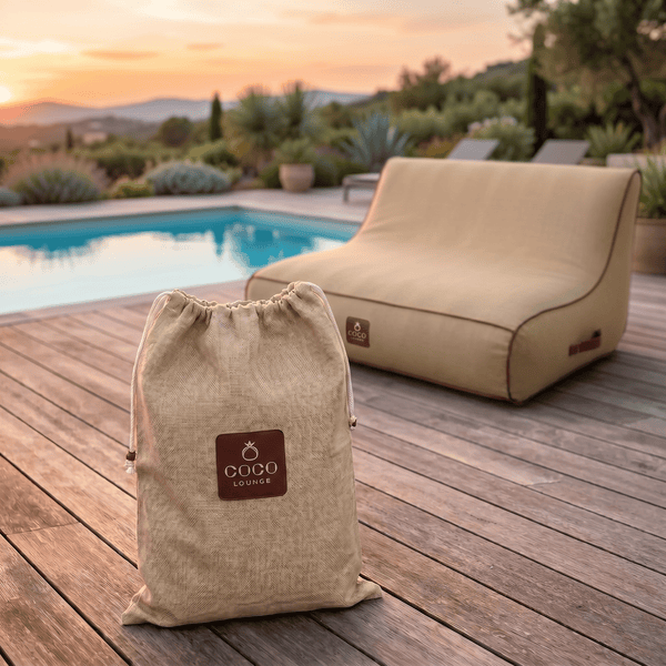 Sitzsack und Transportbeutel aus Textil mit Coco Lounge Logo auf einer Holzterrasse am Pool, moderner Gartenstil in einer hellen Umgebung.