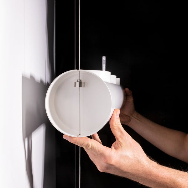 Eine weiße Lüftungsleitung wird von einer Hand gehalten.