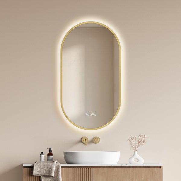 Ovaler Badezimmerspiegel mit LED Beleuchtung und Touch Steuerung montiert über einem Waschtisch mit Aufsatzwaschbecken und Armatur.