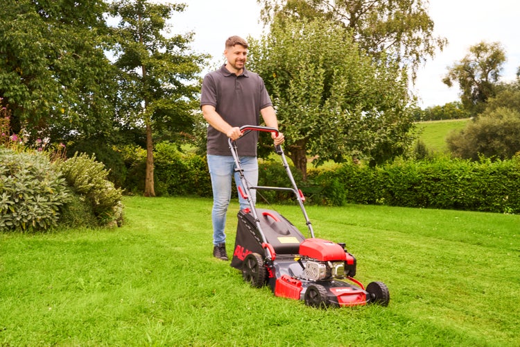 Mann mäht eine Rasenfläche im Garten mit einem Benzin-Rasenmäher von AL-KO.