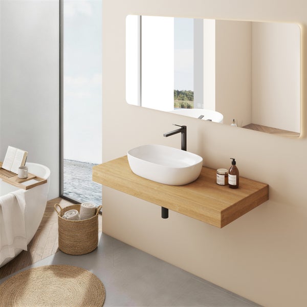 Helles Badezimmer mit weißem Aufsatzwaschbecken auf Holzplatte, schwarzer Armatur, großem LED-Spiegel und freistehender Badewanne.