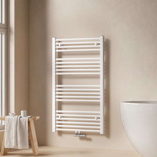 Badezimmer Szene mit einem Handtuchwärmer an der Wand, einem Hocker mit Handtuch und Badutensilien sowie einem Teil einer Badewanne.