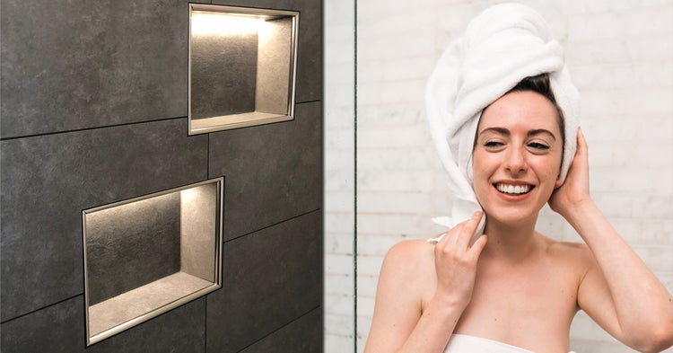 Badezimmerwand mit zwei beleuchteten Nischen und einer Frau mit einem Handtuch auf dem Kopf.