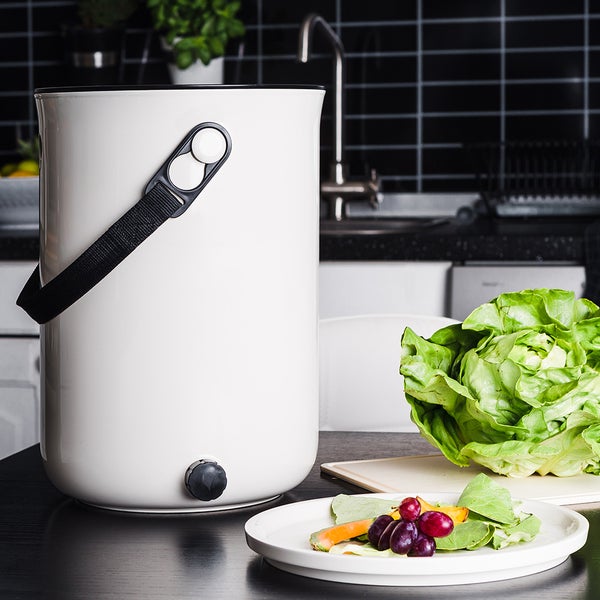 Komposteimer mit Griffband neben Salat und Essensresten
