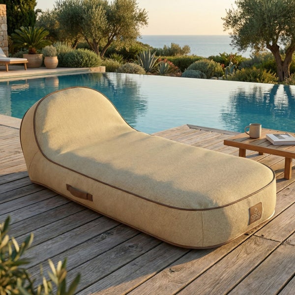 Ergonomisch geformte Gartenliege aus strukturiertem Stoff mit Tragegriff auf einer Holzterrasse am Pool mit Meerblick.