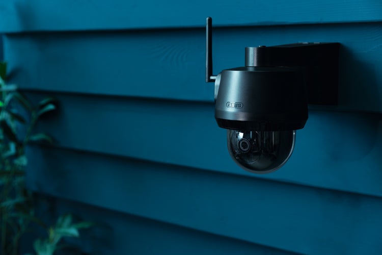 ABUS Überwachungskamera für den Außenbereich, an einer Holzwand montiert, mit Antenne und Glaskuppel.