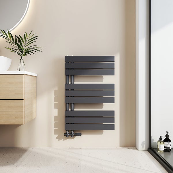 Moderner anthrazitfarbener Design-Badheizkörper mit einseitig offenen horizontalen Lamellen in einem hellen Badezimmer neben einem Waschtisch aus Holz.