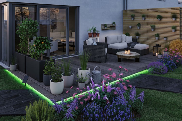 Terrasse mit Gartenmöbeln, Pflanzen und Beleuchtung für eine angenehme Atmosphäre im Freien