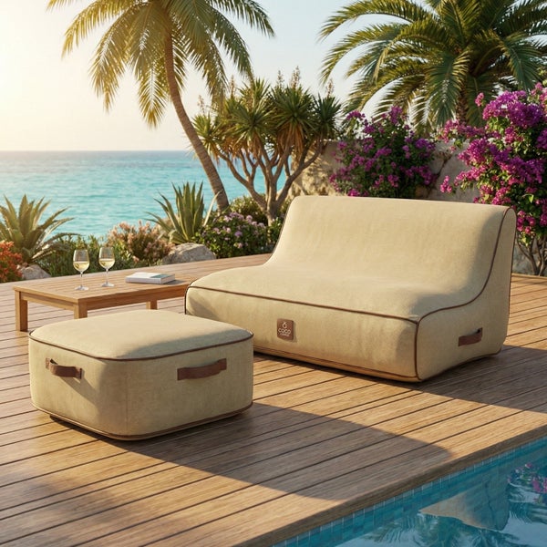 Helles Garten-Lounge-Set aus beigem Stoff mit Sofa und Hocker auf einer Holzterrasse neben einem Pool mit Blick auf das Meer.