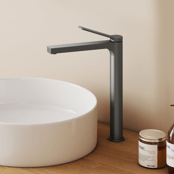 Moderne hohe Waschtischarmatur mit flachem Auslauf neben einem runden Aufsatzwaschbecken auf einer Holzkonsole in einem hellen Badezimmer.