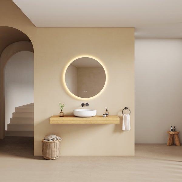 Minimalistisches Badezimmer mit rundem beleuchtetem Spiegel, weißem Aufsatzwaschbecken auf einer Holzkonsole und schwarzer Wandarmatur.