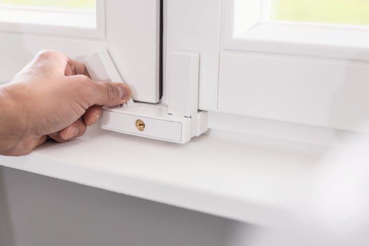 Fenstersicherung für zweiflügelige Fenster an einem weißen Fensterrahmen mit Handbedienung.