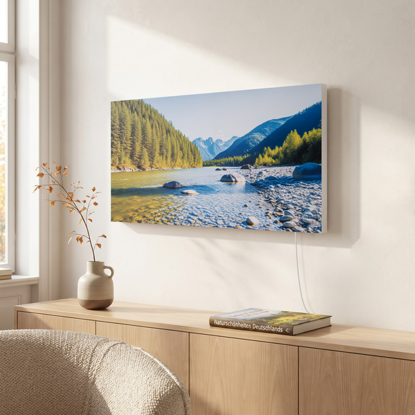 Infrarotheizung mit Landschaftsmotiv an einer Wand über einem Holzsideboard in einem hellen Wohnraum.