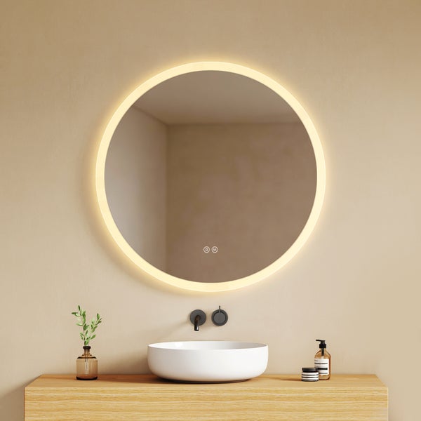 Moderner runder Badezimmerspiegel mit LED-Beleuchtung über einem weißen Aufsatzwaschbecken auf einem hellen Holzwaschtisch.