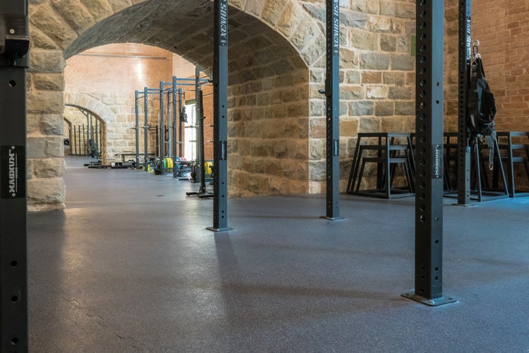 Innenansicht eines Fitnessstudios mit Geräten und Steinbögen