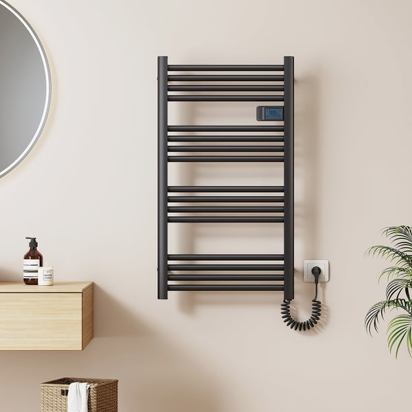 Elektrischer Handtuchheizkörper in Schwarz mit Digitalanzeige und Spiralkabel in einem modernen, hellen Badezimmer.