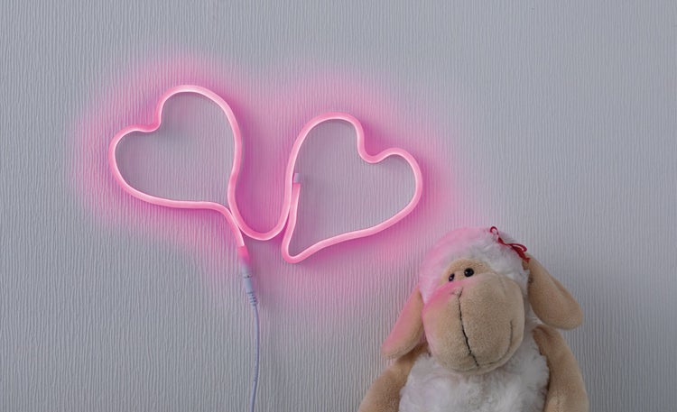 Dekoratives Herz-Neonlicht neben einem Stoffschaf