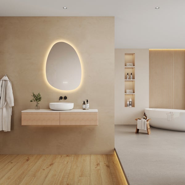 Modernes helles Badezimmer mit organisch geformtem LED Spiegel wandhängendem Holzwaschtisch weißem Aufsatzbecken und freistehender Badewanne