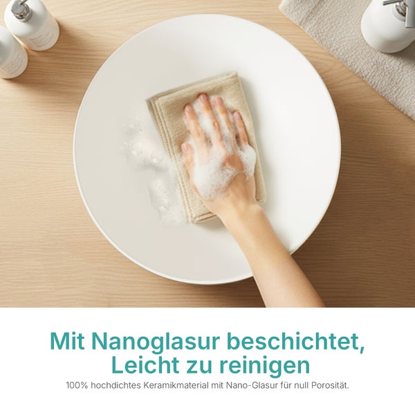 Hand reinigt weißes Keramik-Waschbecken mit Tuch und Schaum, zeigt die pflegeleichte Nanoglasur.