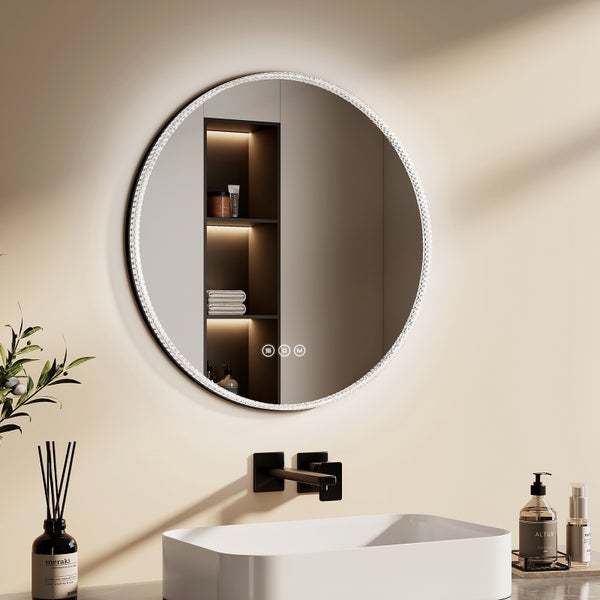 Badezimmerszene mit einem runden Spiegel mit Beleuchtung, einem Waschbecken und Dekorationsartikeln