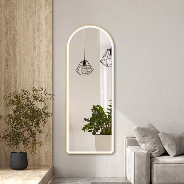 Wandspiegel mit Rundbogen, Goldrahmen und LED-Beleuchtung in einem modernen Wohnzimmer neben einem Sofa.
