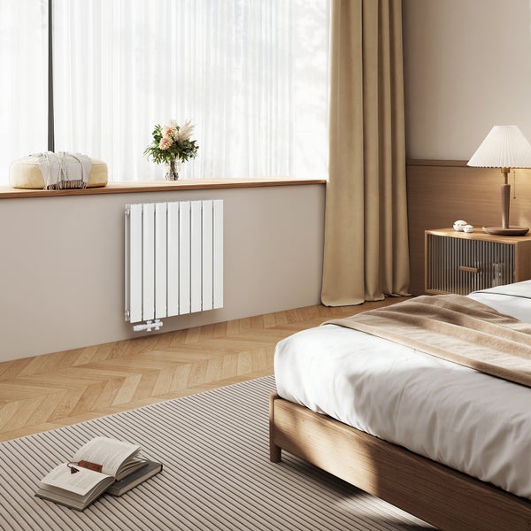 Moderner Flachheizkörper unter einem Fenster in einem gemütlich eingerichteten Schlafzimmer mit Holzboden.
